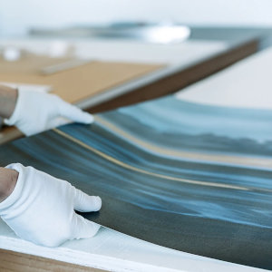Artisan tendant la toile &agrave; la main sur des barres de bois massif