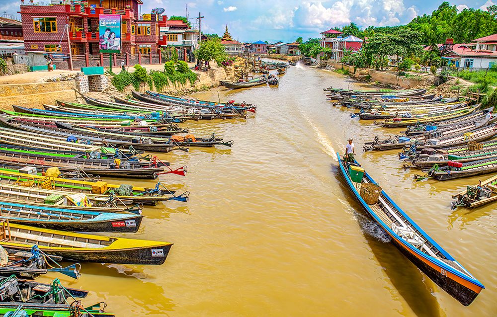 Nyaungshwe, Myanmar. Wide angle long motor boats lining the canal which runs into Inle Lake. art print by Murray McCallum for $57.95 CAD