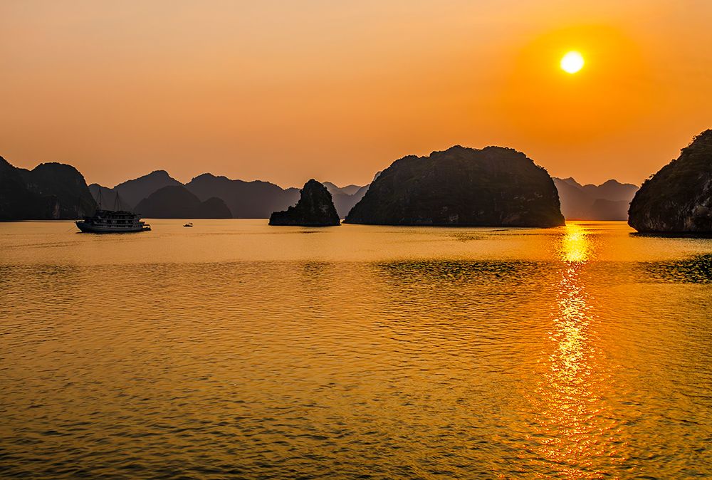 Ha Long Bay, Vietnam. Boat carrying tourists at sunset through the limestone karsts and islets. art print by Murray McCallum for $57.95 CAD
