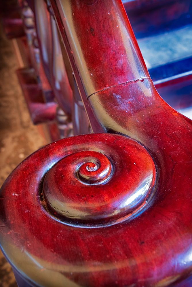 Snail shell-like curve on red wooden bannister handrail in Trinidad-Cuba art print by Janis Miglavs for $57.95 CAD