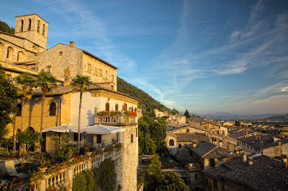 Italy- Umbria. Evening light on flower covered buildings overlooking the medieval town of Gubbio. art print by Julie Eggers for $57.95 CAD