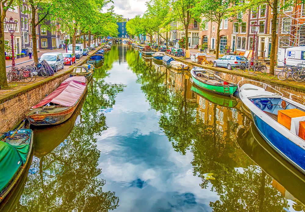Amsterdam, Netherlands. houseboats, motor boats and sail boats lining a canal on a summer day. art print by Murray McCallum for $57.95 CAD