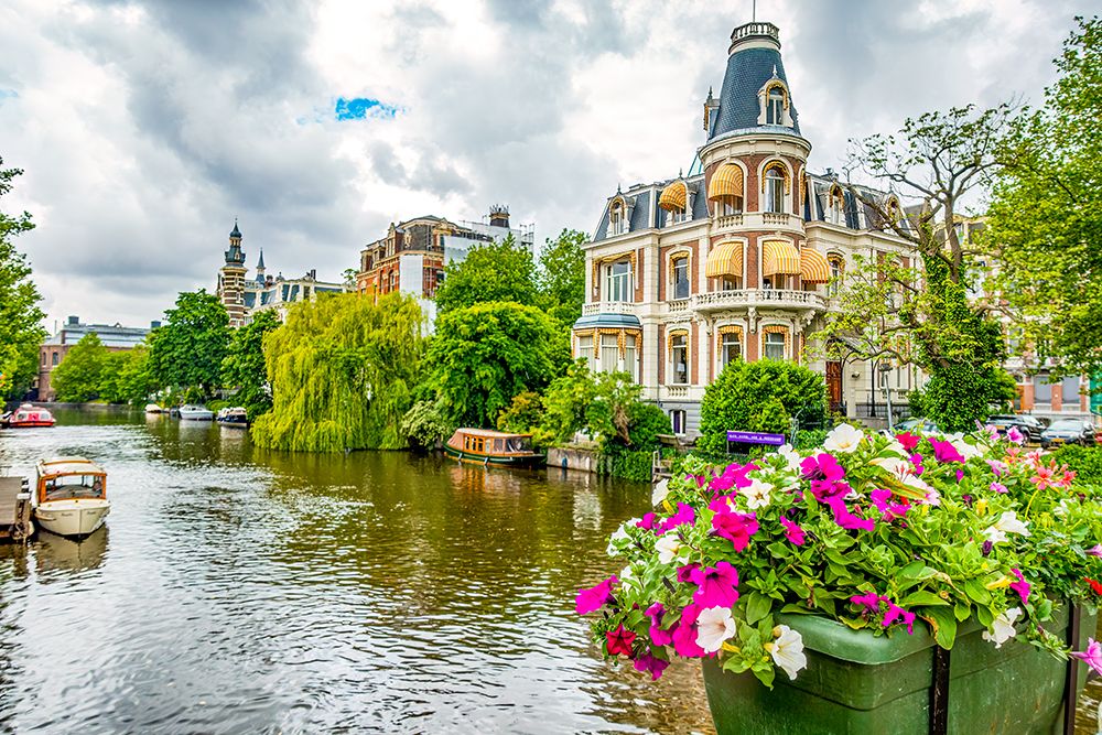 Amsterdam, Netherlands. historic houses on tree and flower lined canal. art print by Murray McCallum for $57.95 CAD