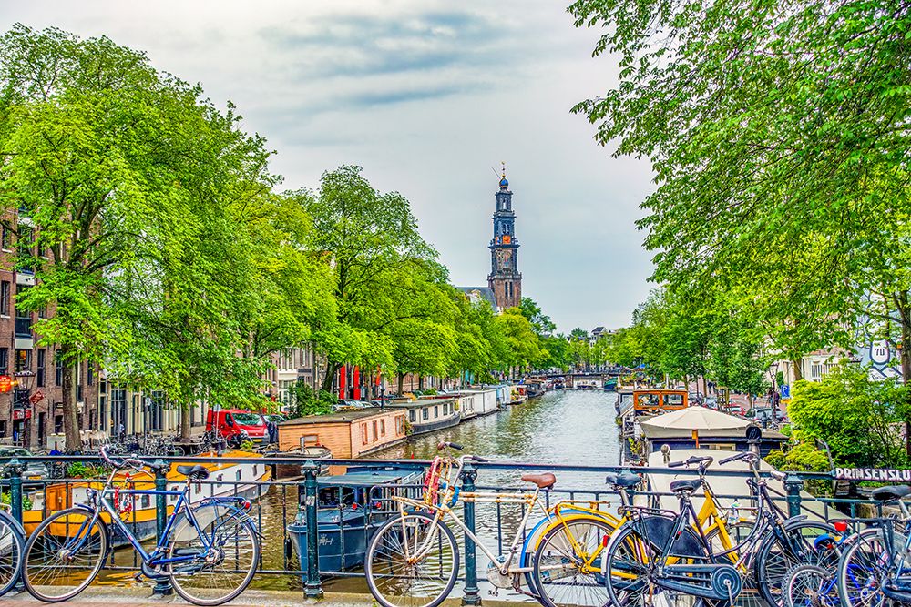 Amsterdam, Netherlands. Munttoren Tower at end of canal lined with boats and trees. art print by Murray McCallum for $57.95 CAD