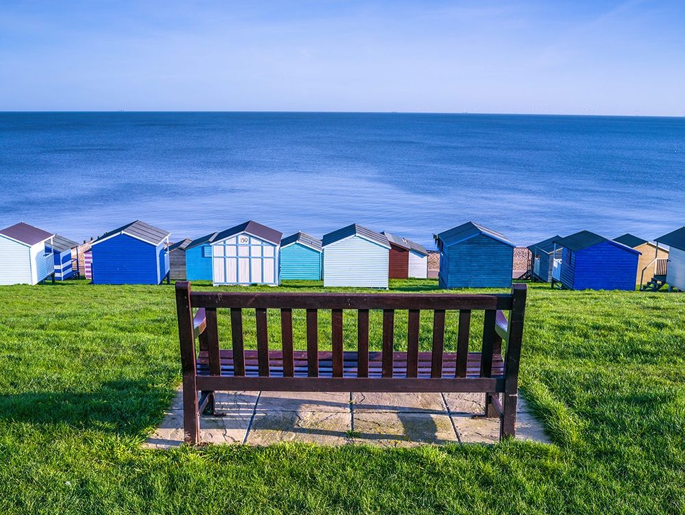 Bench on lawn with beach huts in background art print by Assaf Frank for $57.95 CAD