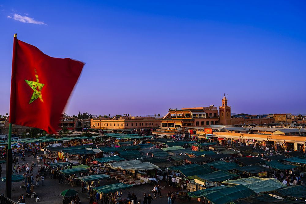 Vibrant City Market At Dusk With A Red Flag And Historical Architecture. Marrakesh, Morocco art print by Alberto Biscaro for $57.95 CAD