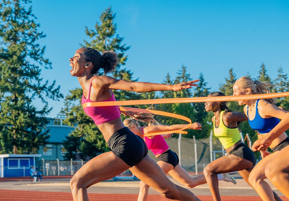 Four Athletes Sprinting To Finish Line On An Outdoor Track With Trees. Wa, USA art print by Pete Saloutos for $57.95 CAD