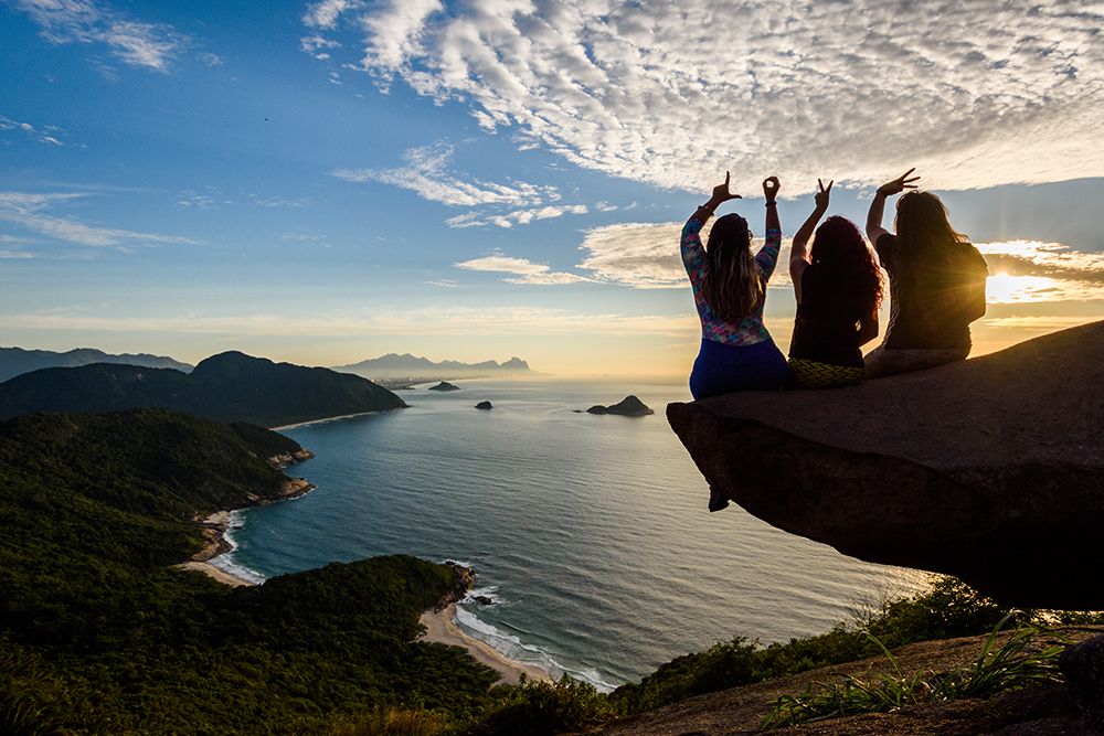 Three People Sitting On Rock At Sunset, Pedra Do Telegrafo, Rio De Janeiro, Brazil art print by Vitor Marigo for $57.95 CAD