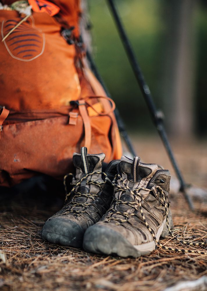A Close Up Of Hiking Boots Next To An Orange Hiking Backpack In Maine art print by Chris Bennett for $57.95 CAD