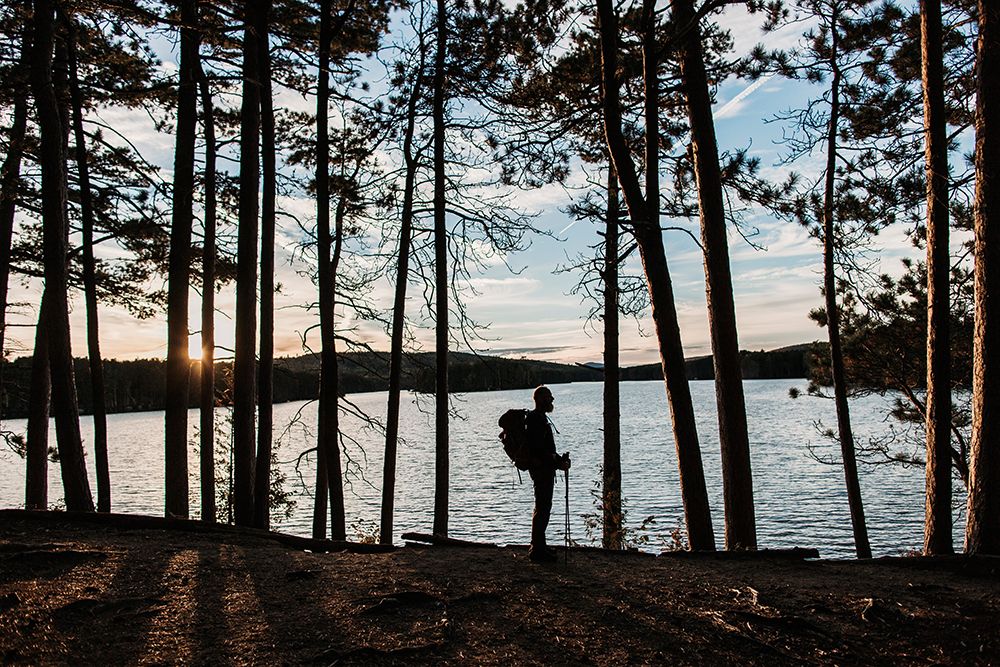 A Hiker With A Backpack Stands Next To A Lake At Sunset In Maine art print by Chris Bennett for $57.95 CAD