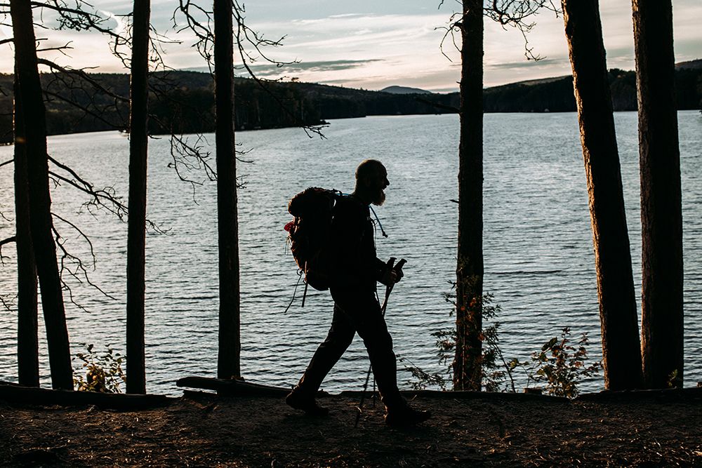 A Male Walker With A Backpack Hikes Along The Edge Of A Lake In Maine art print by Chris Bennett for $57.95 CAD