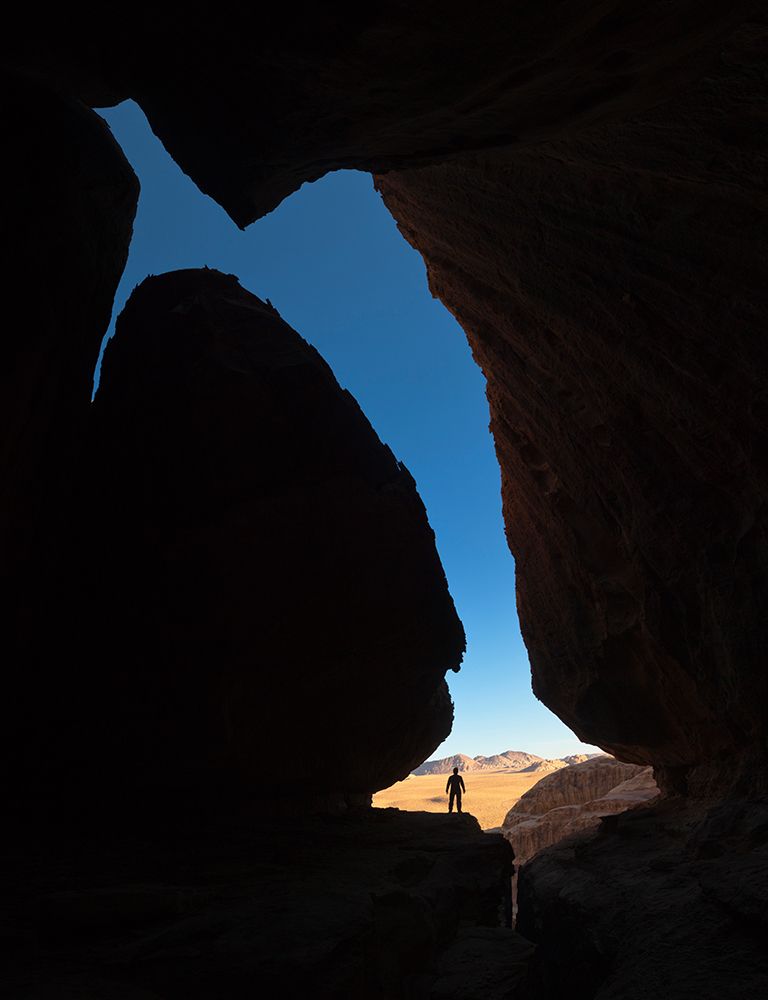 A Young Man Stands In A Cave Looking Out Towards The Desert Outside In Wadi Rum, Jordan. art print by Ethan Welty for $57.95 CAD