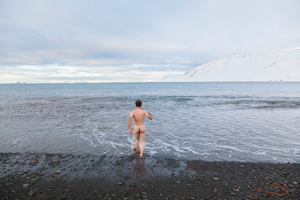 A Young Man Steps Naked Into The Frigid Waters Of Adventfjorden Outside Longyearbyen, Svalbard. art print by Ethan Welty for $57.95 CAD