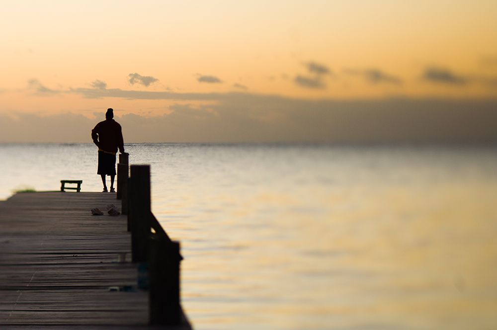 A Man Watches The Sun Rise From A Dock On Ambergris Caye, Belize. art print by Kevin Steele for $57.95 CAD