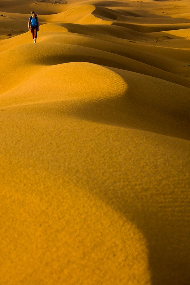 Female Hiking In Red / Orange Sand Dunes In Desert. art print by Gabe Rogel for $57.95 CAD