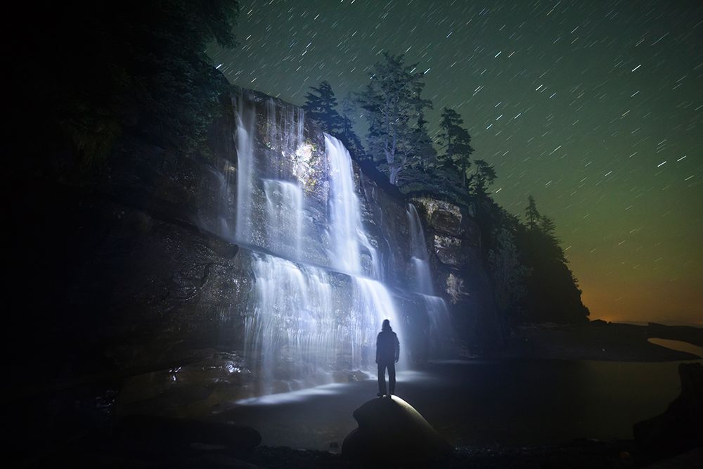A Backpacker Stands Facing Tsusiat Falls At Night, West Coast Trail, British Columbia, Canada. art print by Ethan Welty for $57.95 CAD