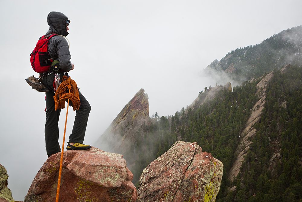 Young Man Looks Out Towards Flatirons, Shrouded In Mist, From Summit Of First Flatiron Colorado. art print by Ethan Welty for $57.95 CAD