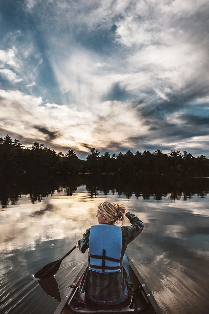 Woman Paddles Canoe Across Beautiful Lake In Maine At Sunset art print by Chris Bennett for $57.95 CAD