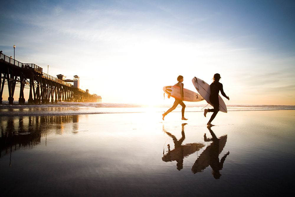 Two Surfer Run Accross The Beach At Sunset. art print by Jay Reilly for $57.95 CAD