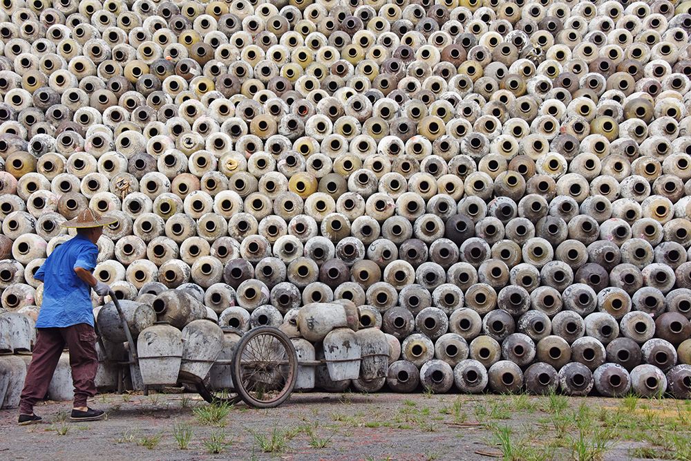 Man pushing cart loaded with wine jars to the big pile in a winery-Zhejiang Province-China art print by Keren Su for $57.95 CAD