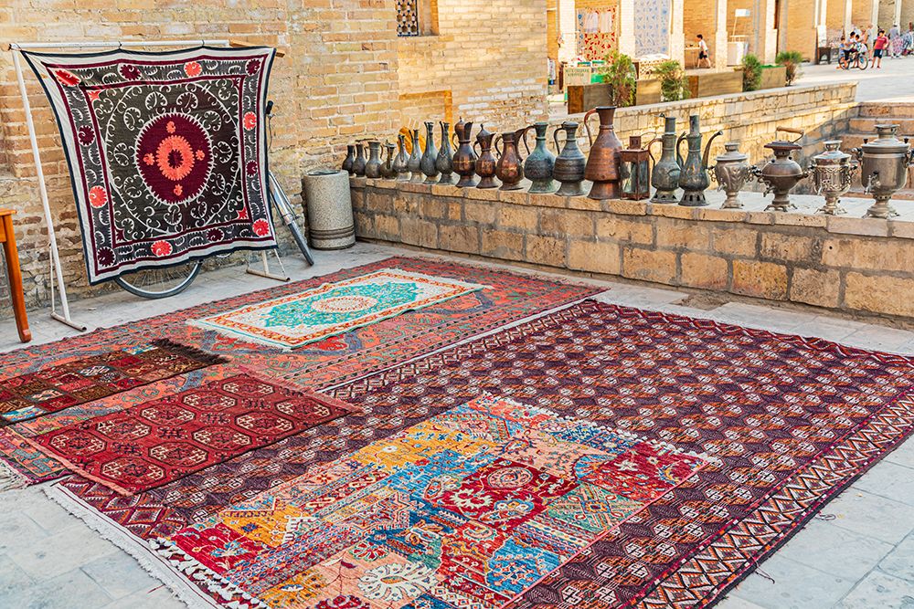 Bukhara, Uzbekistan, Central Asia. Rugs and traditional metal ware displayed for sale in Bukhara. art print by Emily M. Wilson for $57.95 CAD