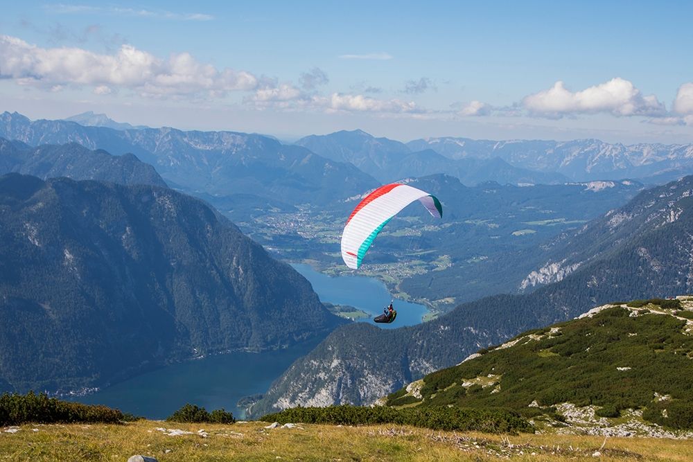 Austria-Dachstein-Paraglider soaring above Lake Hallstatt and the surrounding mountains art print by Hollice Looney for $57.95 CAD
