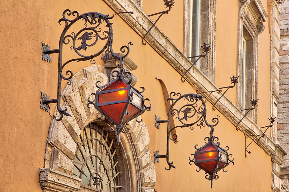 Italy- Umbria- Assisi. Wrought iron dragon lights on a wall above an entrance. art print by Julie Eggers for $57.95 CAD
