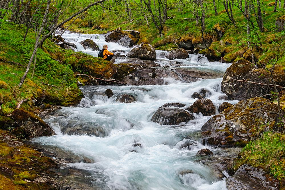 Norway-Nordland-Tysfjord. Woman sitting along Storelva-river that flows from Stetind mountain art print by Fredrik Norrsell for $57.95 CAD