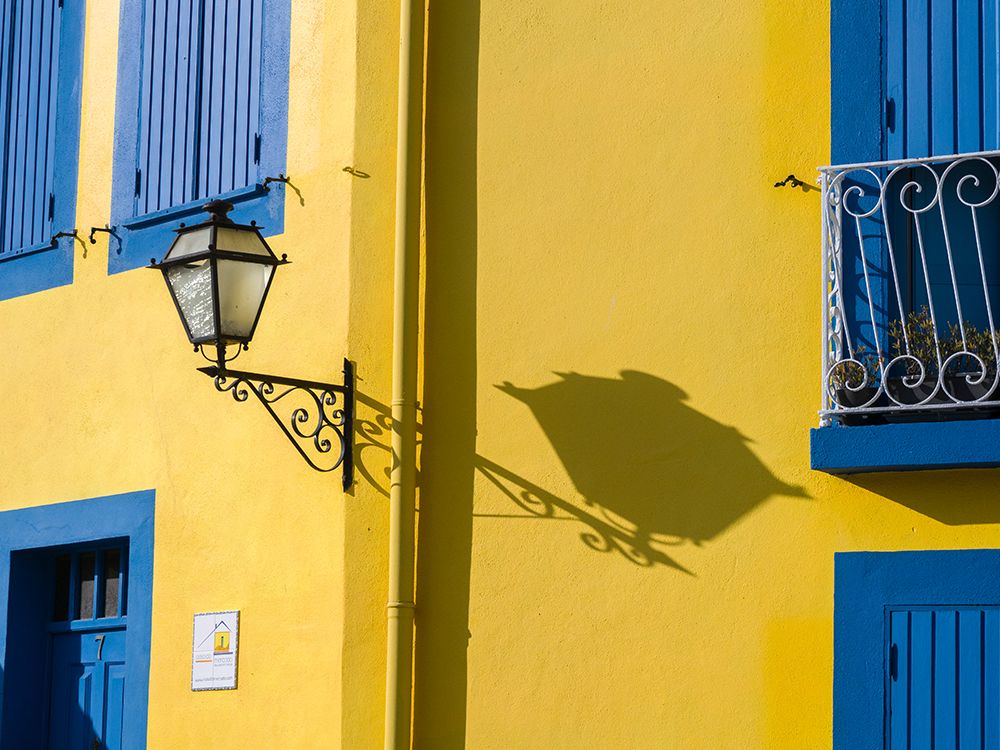 Portugal-Aveiro-Shadow of street lantern on colorful yellow building with bright blue shutters art print by Julie Eggers for $57.95 CAD