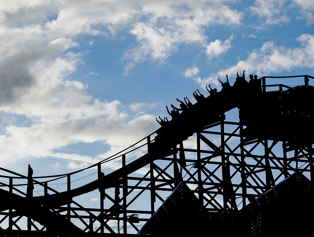 Silhouette of people raising their hands on a roller coaster. art print by Merrill Images for $57.95 CAD