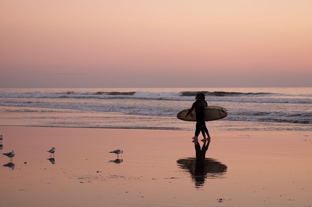 Surfers cast a shadow on wet sand as they walk on Huntington Beach at sunset California-USA art print by Sergio Pitamitz for $57.95 CAD