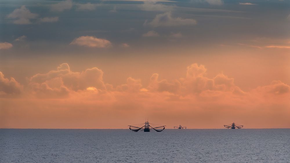 Fishing boats deep out to sea against the backdrop of dramatic sunset clouds and sky art print by Sheila Haddad for $57.95 CAD