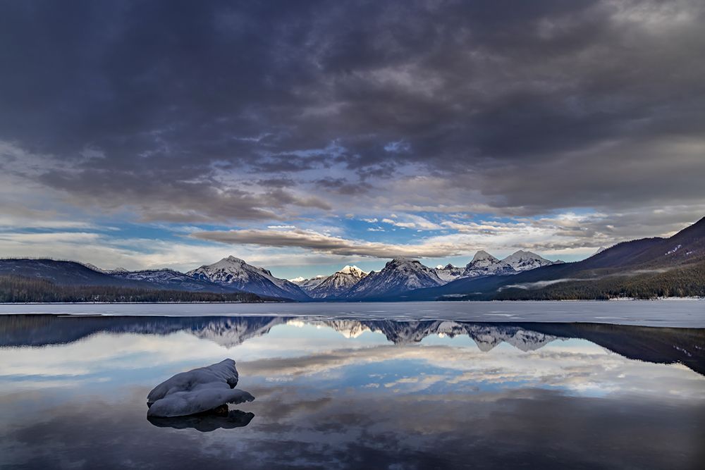 Clouds reflect in opening in the ice on Lake McDonald in Glacier National Park, Montana, USA. art print by Chuck Haney for $57.95 CAD