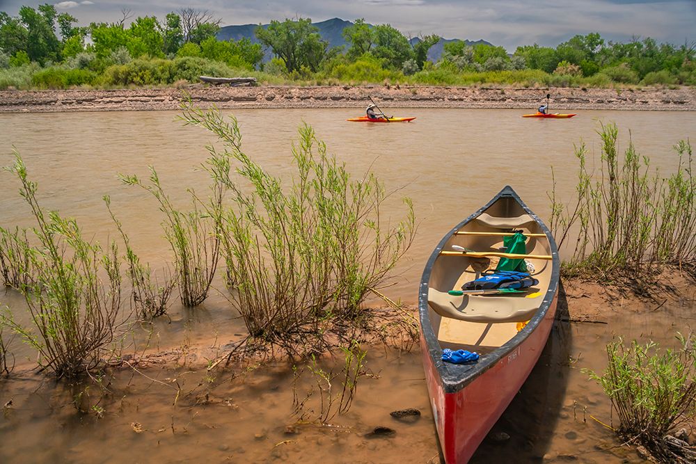 USA, New Mexico, Rio Grande River. Empty canoe on riverbank and kayakers on river. art print by Jaynes Gallery for $57.95 CAD