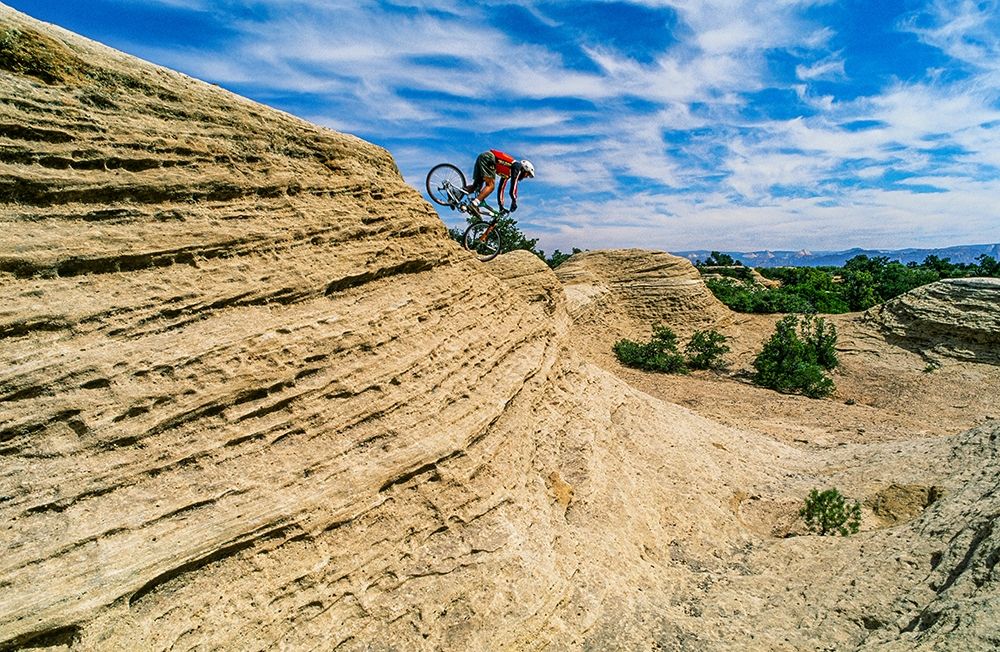Mountain biker balances courage and danger and attempting to avoid crash on Red Rock-Utah-USA (MR) art print by Howie Garber for $57.95 CAD