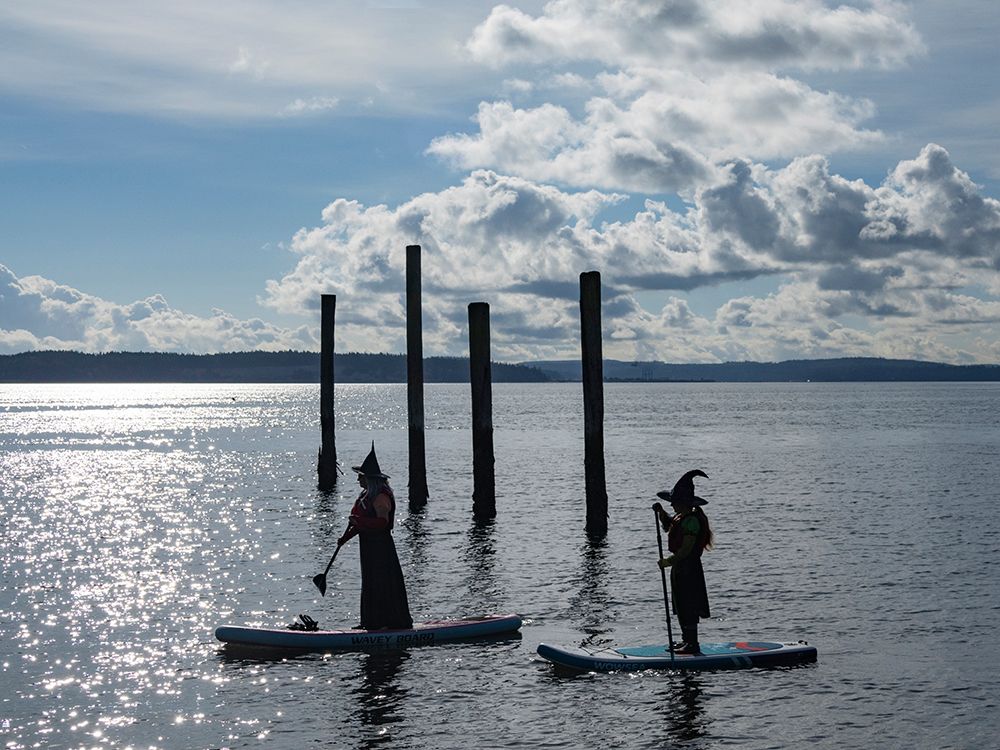 Port Townsend, Washington State. Silhouettes of two women dressed as witches on paddleboards. art print by Merrill Images for $57.95 CAD