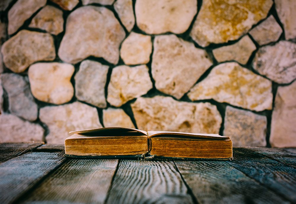 Old Open Book On Old Wooden Table On A Background Of Stone Walls art print by Andre Solovie for $57.95 CAD